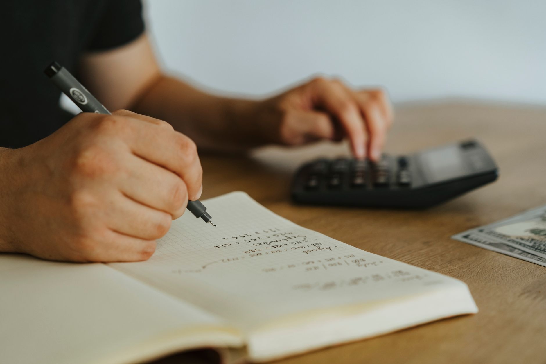 Personne notant des dépenses dans un carnet avec une calculatrice