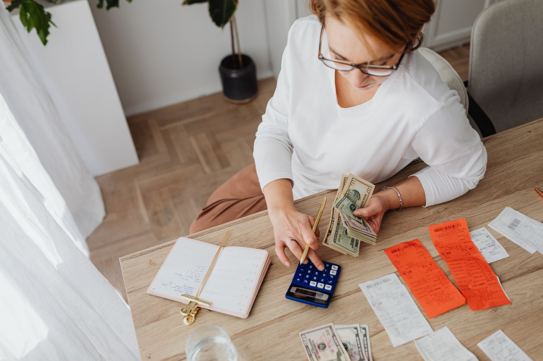 Personne calculant son budget mensuel avec une calculatrice et des factures